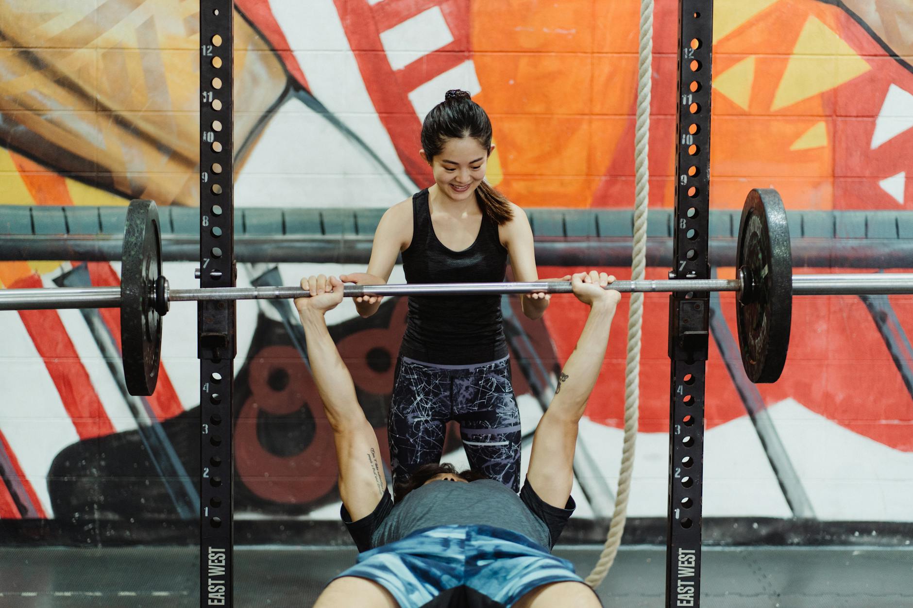 Azjatycka para trenująca wyciskanie sztangi na ławce w siłowni